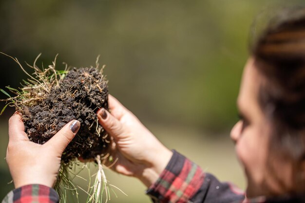 Agricultora segura o solo nas mãos monitorando a saúde do solo em uma fazenda em uma cultura