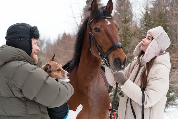 Agricultores (hombre y mujer) caminando con perro y caballo en día de invierno en el campo