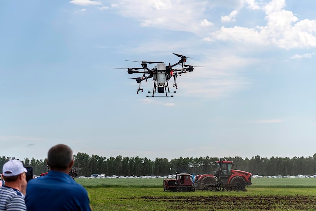 Los agricultores observan y controlan de forma remota un dron para procesar campos drone agrícola rociar un campo