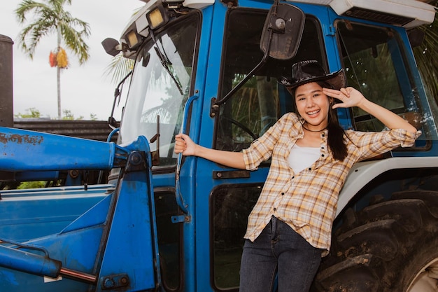 Foto agricultura de agricultor de retrato jovem fica em um trator dirigindo uma colheitadeira no campo.