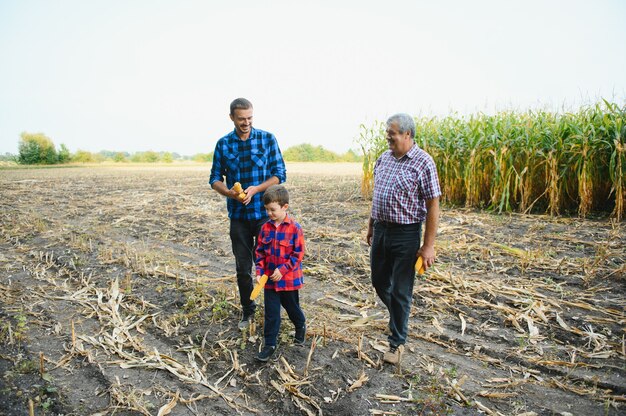 Agricultura familiar. Abuelo de agricultores con nieto en un campo de maíz. abuelo experimentado le explica a su nieto la naturaleza del crecimiento de las plantas.