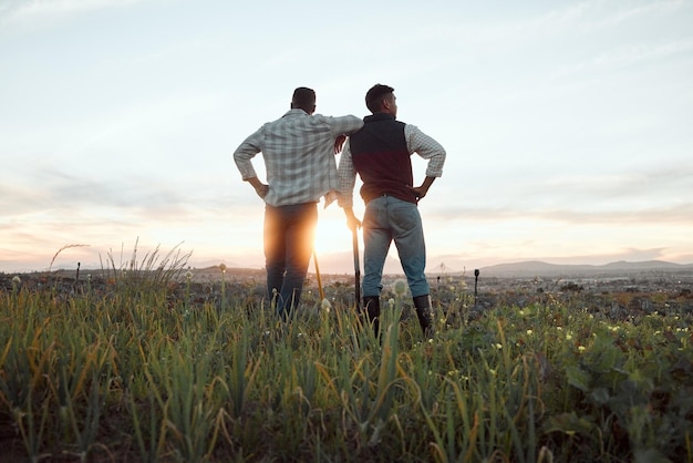 Agricultura gera bom senso Foto de dois fazendeiros em uma fazenda durante o pôr do sol