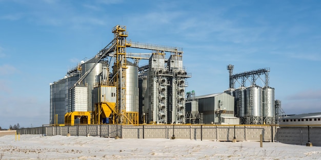 Agro-Silos-Getreideaufzug am Wintertag auf schneebedeckten Feldern Silos auf Agroprocessing-Produktionsanlagen zur Verarbeitung, Trocknung, Reinigung und Lagerung von landwirtschaftlichen Produkten, Mehl, Getreide und Getreide