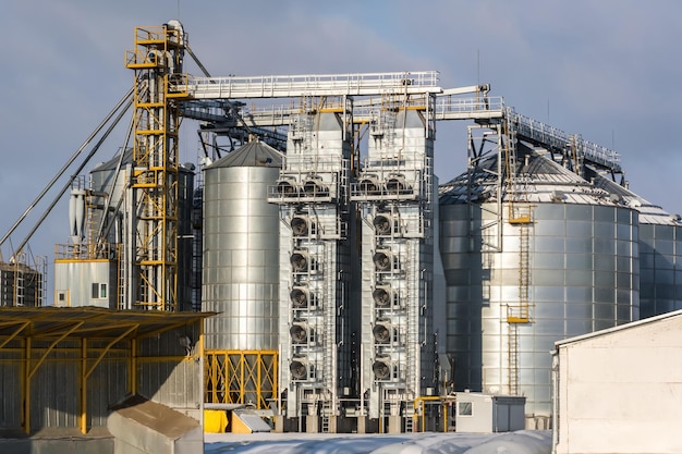 Agro-Silos-Getreideaufzug am Wintertag auf schneebedeckten Feldern Silos auf Agroprocessing-Produktionsanlagen zur Verarbeitung, Trocknung, Reinigung und Lagerung von landwirtschaftlichen Produkten, Mehl, Getreide und Getreide