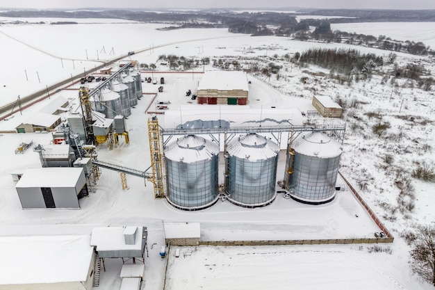 Agro-Silos-Getreideaufzug an Wintertagen auf schneebedeckten Feldern Silos auf Agroprocessing-Produktionsanlagen zur Verarbeitung, Trocknung, Reinigung und Lagerung landwirtschaftlicher Produkte