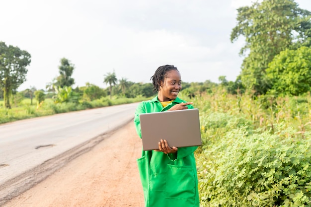 Agrónomo de granja de sexo femenino negro que controla un campo agrícola usando la computadora portátil