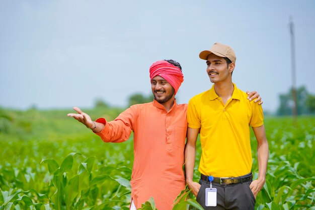 Agrônomo indiano com fazendeiro no campo de agricultura verde.