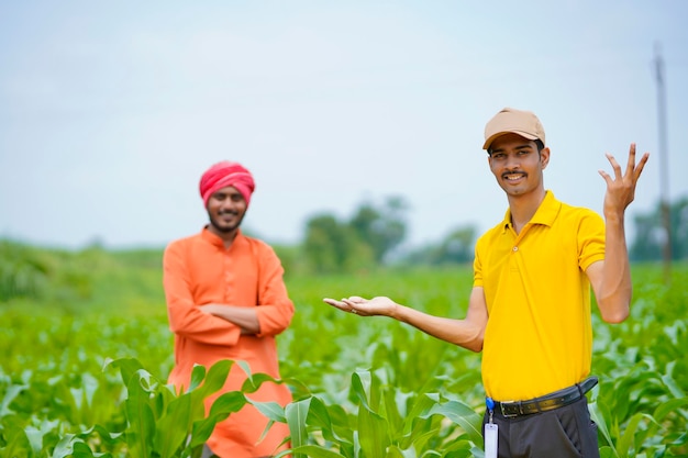 Agrônomo indiano com fazendeiro no campo de agricultura verde.