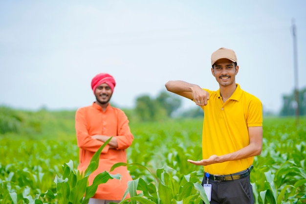 Agrônomo indiano com fazendeiro no campo de agricultura verde.