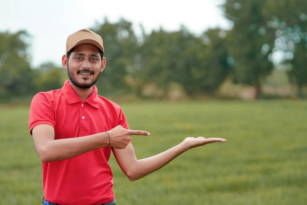 Agrônomo indiano dando expressão com a mão no campo da agricultura.