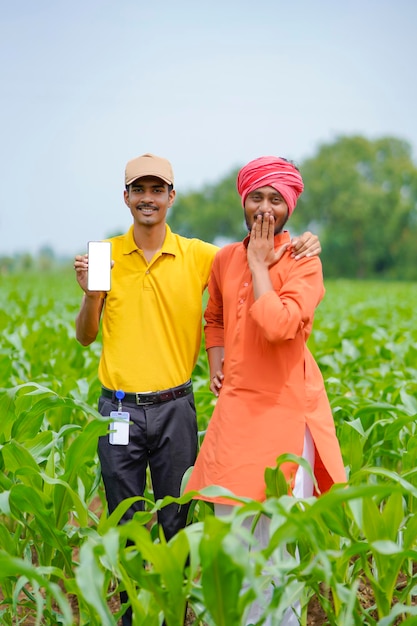 Agrônomo indiano mostrando smartphone com agricultor no campo de agricultura.