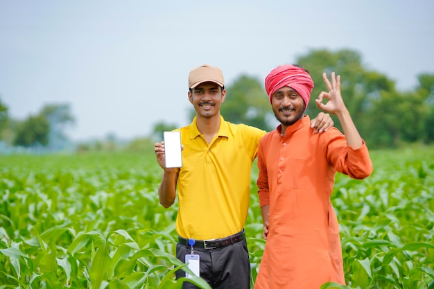 Agrónomo indio mostrando smartphone con agricultor en el campo de la agricultura.