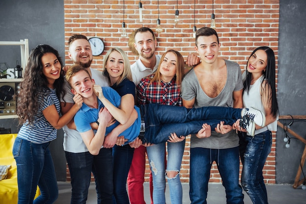 Agrupe o retrato de meninos e meninas multiétnicas com roupas da moda coloridas, segurando o amigo posando em uma parede de tijolos, pessoas de estilo urbano se divertindo, s sobre estilo de vida de juventude União