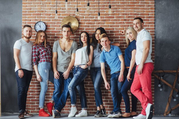 Agrupe o retrato de meninos e meninas multiétnicas com roupas da moda coloridas, segurando o amigo posando em uma parede de tijolos, pessoas de estilo urbano se divertindo, s sobre estilo de vida de juventude União