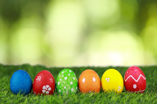 Agrupe ovos da páscoa bonitos coloridos e decorados na grama verde na natureza com fundo verde do bokeh. imagem de publicidade conceito de festival de páscoa com espaço livre.