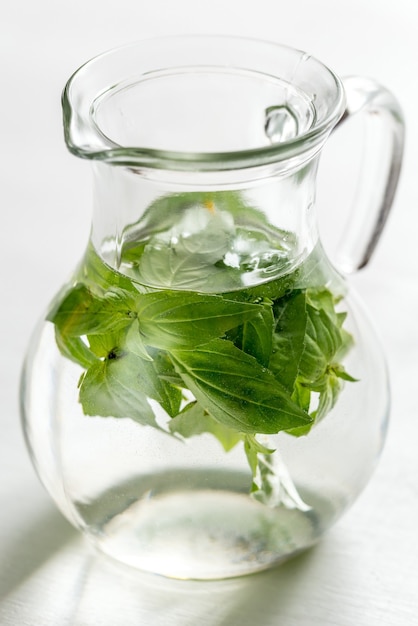 Agua con albahaca fresca en la jarra de vidrio.