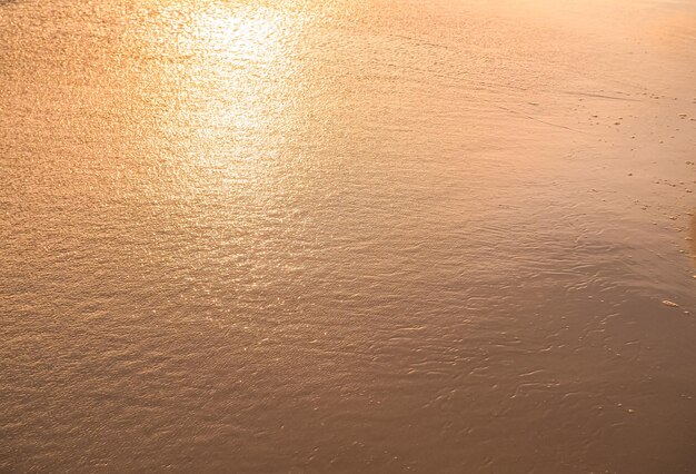 Agua y arena en la playa al atardecer.