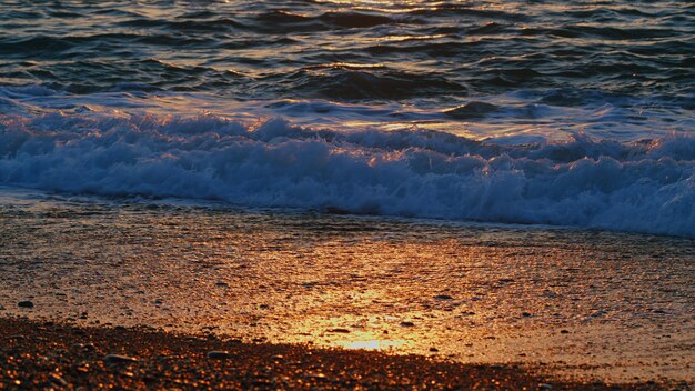 Foto el agua del atardecer refleja las ondas en la luz del sol superficie ondulada de agua de mar naranja y dorado en la puesta del sol