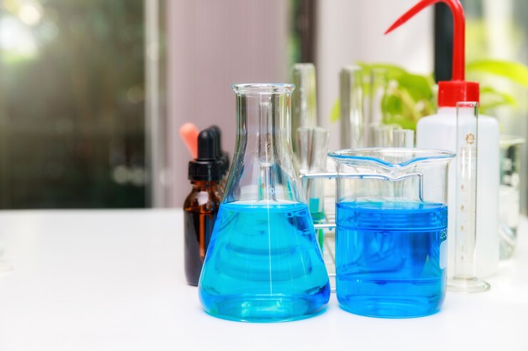 Foto água azul do experimento no copo e no frasco no laboratório de ciências químicas.