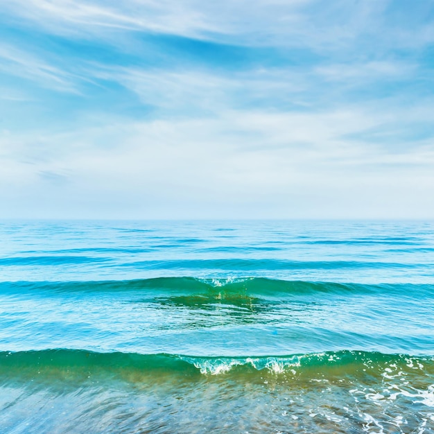 Foto Água azul do mar com ondas e nuvens brancas no céu paisagem tropical calma