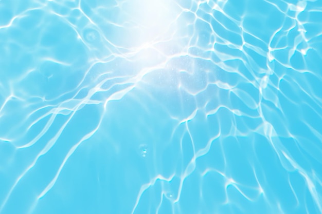 Un agua azul en una piscina con el sol brillando sobre ella.