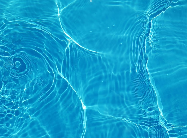 Un agua azul en una piscina con el sol brillando sobre ella.