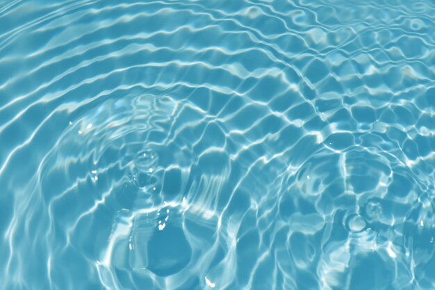 Un agua azul en una piscina con el sol brillando sobre ella