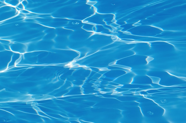 Un agua azul en una piscina con el sol reflejado en el agua.