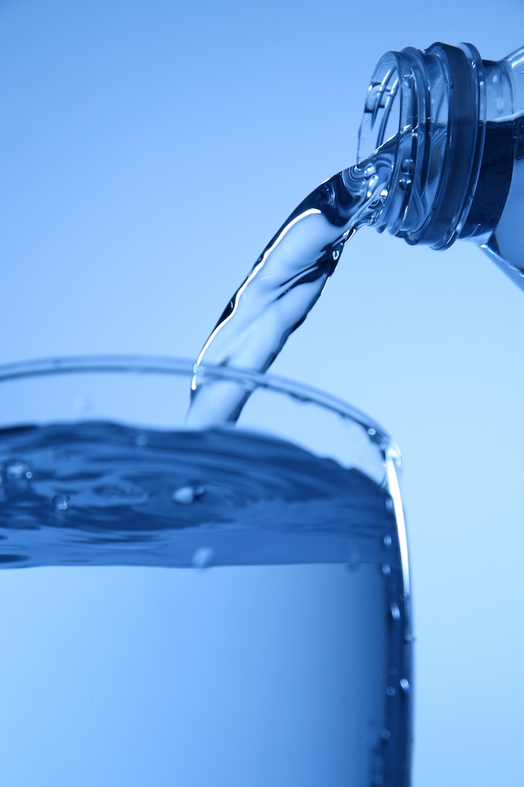 Foto agua para beber vertida en un vaso, primer plano.