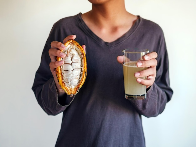 Foto agua de cacao fresca en vaso y vaina de cacao amarillo maduro cortada a mitad con semillas de cacao blanco en