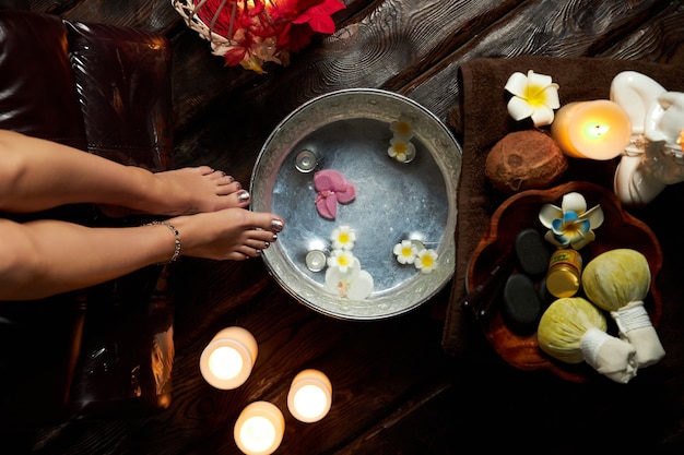 Agua caliente con flores para humedecer los pies, tratamientos de spa, velas y frutas.