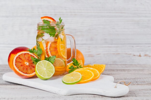 Agua de cítricos y hierbas para desintoxicar o hacer dieta en botellas de vidrio sobre tabla de madera