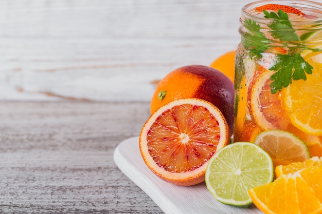 Agua de cítricos y hierbas para desintoxicar o hacer dieta en botellas de vidrio sobre tabla de madera