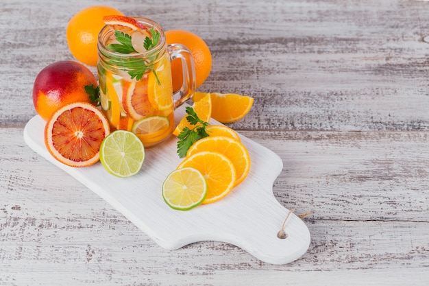 Agua de cítricos y hierbas para desintoxicar o hacer dieta en botellas de vidrio sobre tabla de madera