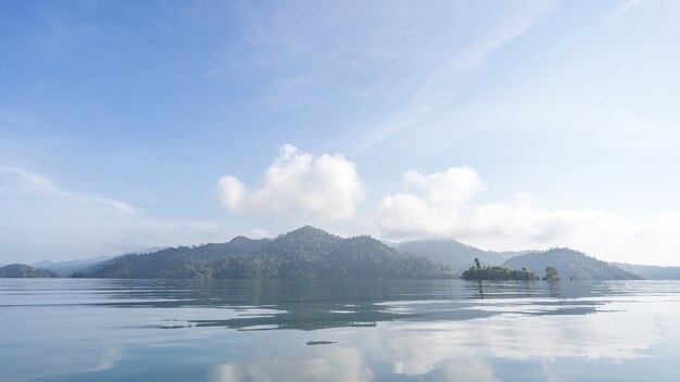 Água clara bonita em Cheow Lan Lake com luz da manhã, reflexão do céu azul