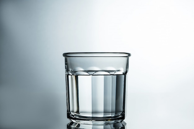 Agua clara como el cristal. Agua purificada en un vaso sobre una mesa gris. Concepto de agua pura.