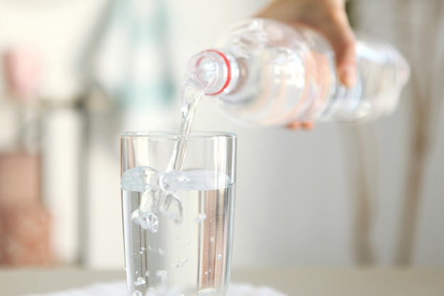 Agua clara en un vaso y una botella sobre la mesa.