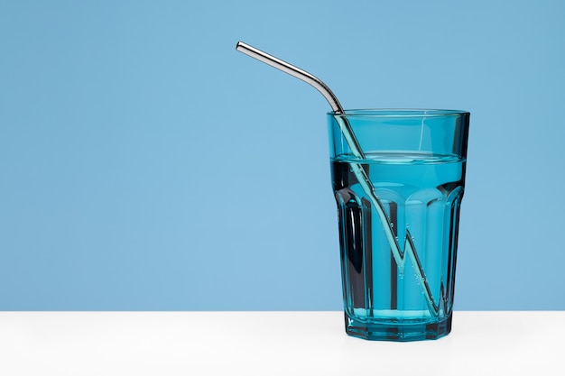 Agua clara en un vaso grande azul con una pajita