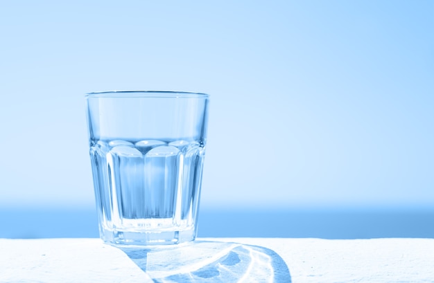 Agua clara en un vaso transparente con el fondo del mar. Concepto de estilo de vida saludable.