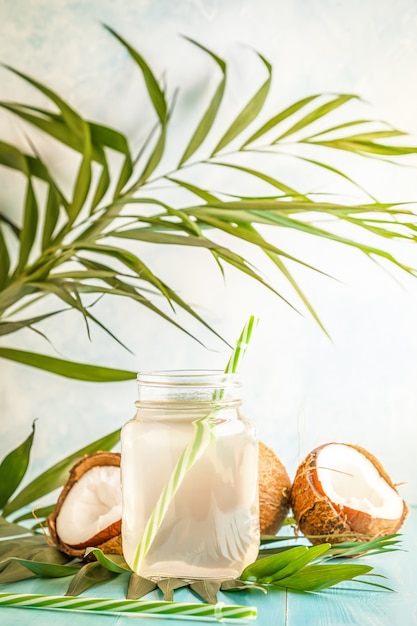 Foto agua de coco y cocos sobre un fondo con hojas tropicales