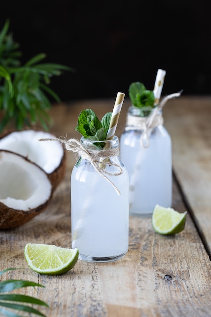 Agua de coco fresca en botella de vidrio sobre la mesa. Bebida vegetariana