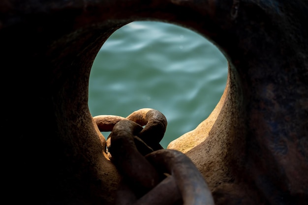 El agua corriente del mar se puede ver a través del agujero del ancla del viejo barco