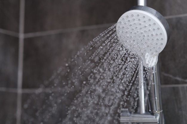 Foto el agua corriente sale del mezclador de ducha cromado. concepto de accesorios de baño