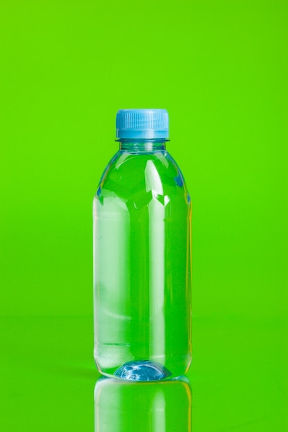 Agua cristalina en una botella sobre fondo verde