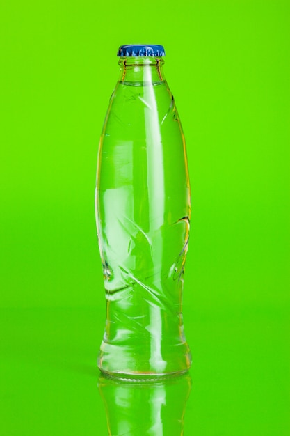 Agua cristalina en una botella en verde