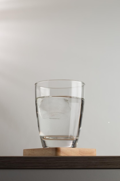 Agua y cubitos de hielo en un vaso en los posavasos de madera