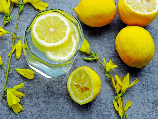 Água de desintoxicação com suco de limão e flores amarelas nos galhos.