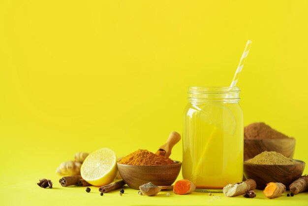 Água de limão com curcuma de gengibre pimenta preta Conceito de bebida quente vegan Ingredientes para bebida de açafrão de laranja em fundo amarelo claro