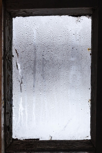 Agua del derretimiento del hielo en la superficie de la ventana empañada