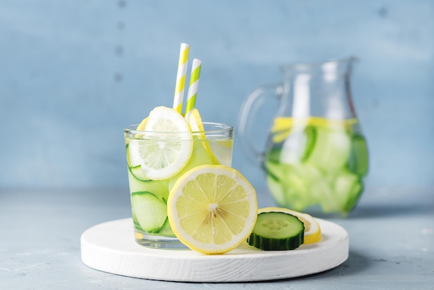 Agua de desintoxicación con bebida de verano de pepino y limón en frascos de vidrio sobre fondo de hormigón azul